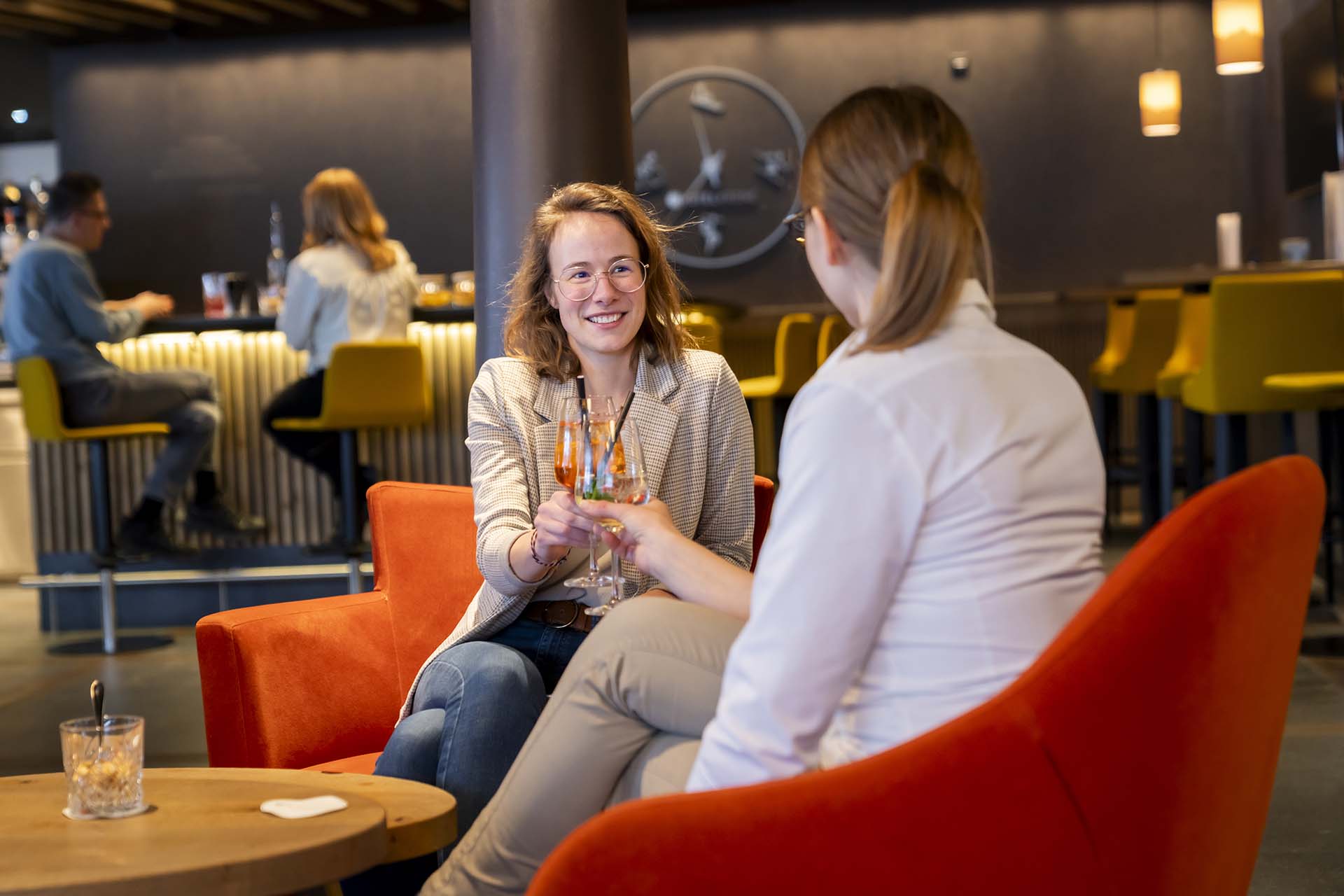 Zwei Freundinnen stoßen in einer Bar mit ihren Getränken an