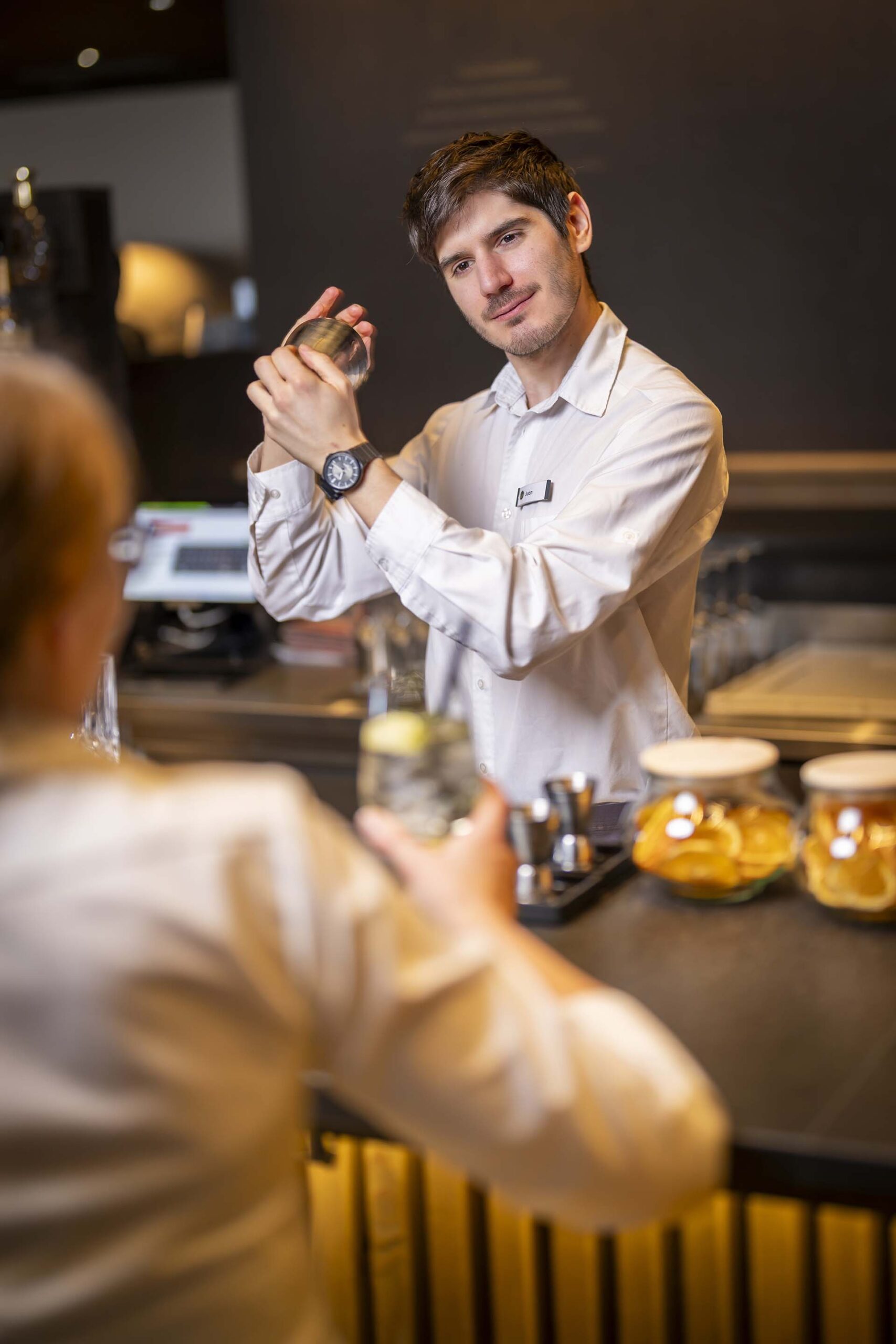 Barkeeper mixt Drink im Shaker vor dem Gast
